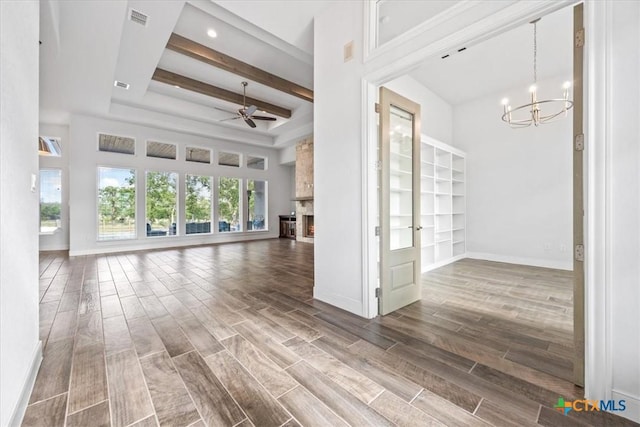 292 Scenic Cyn, New Braunfels, TX 78132 - unfurnished living room with a chandelier, ceiling fan, wood tiled floors, beamed ceiling, and a large fireplace