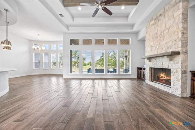 292 Scenic Cyn, New Braunfels, TX 78132 - unfurnished living room featuring a tray ceiling, a stone fireplace, a ceiling fan, dark wood finished floors, and a chandelier