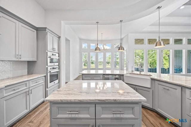 292 Scenic Cyn, New Braunfels, TX 78132 - kitchen with gray cabinets, wood finished floors, a kitchen island, and backsplash