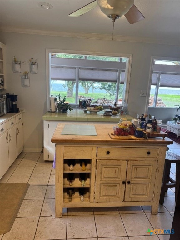 1608 S Virginia St, Port Lavaca, TX 77979 - kitchen with ornamental molding, ceiling fan, light tile patterned floors, and white cabinets