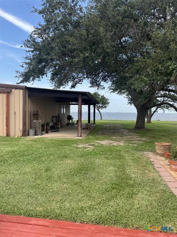 1608 S Virginia St, Port Lavaca, TX 77979 - view of green lawn featuring a water view, a carport, and an outbuilding