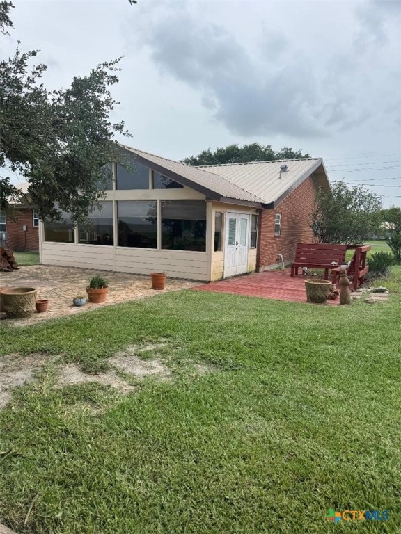 1608 S Virginia St, Port Lavaca, TX 77979 - rear view of house with a deck, a sunroom, a yard, and a metal roof