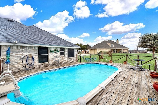 view of swimming pool with a yard and a deck