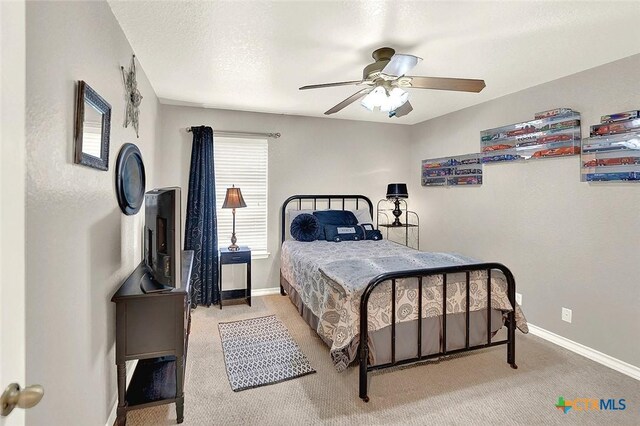 carpeted bedroom featuring ceiling fan and a textured ceiling