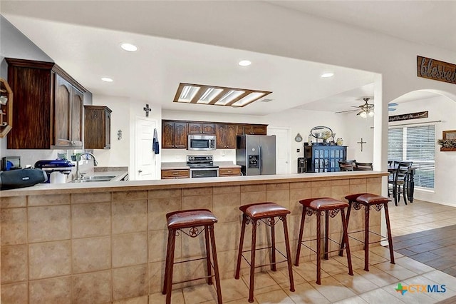 kitchen featuring appliances with stainless steel finishes, a kitchen bar, kitchen peninsula, and sink