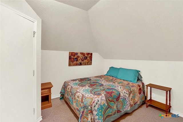 bedroom featuring light carpet, vaulted ceiling, and a textured ceiling