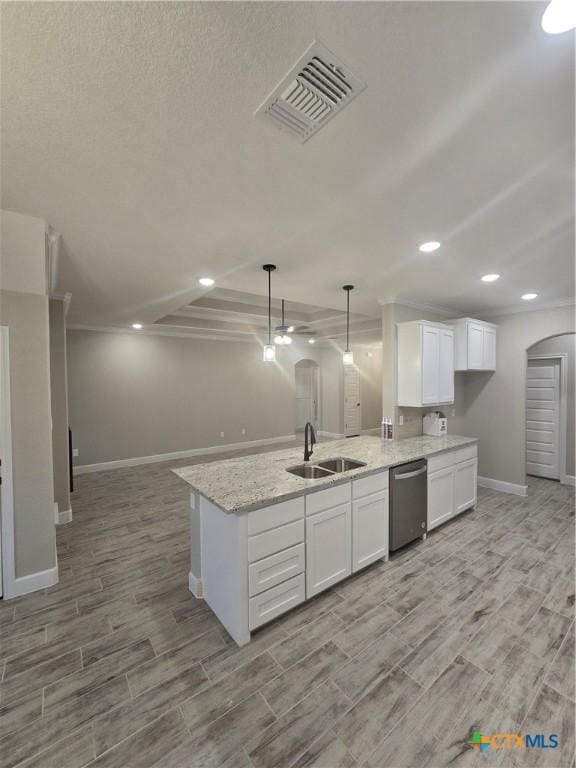 kitchen featuring arched walkways, pendant lighting, visible vents, white cabinetry, and a sink