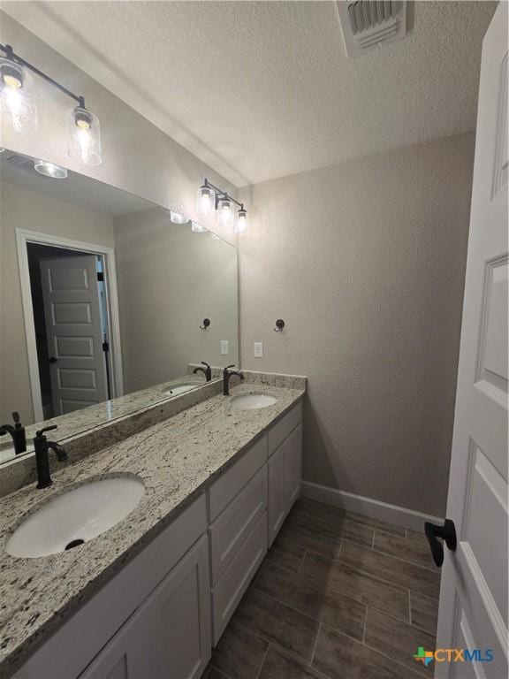 bathroom featuring double vanity, a sink, visible vents, and baseboards