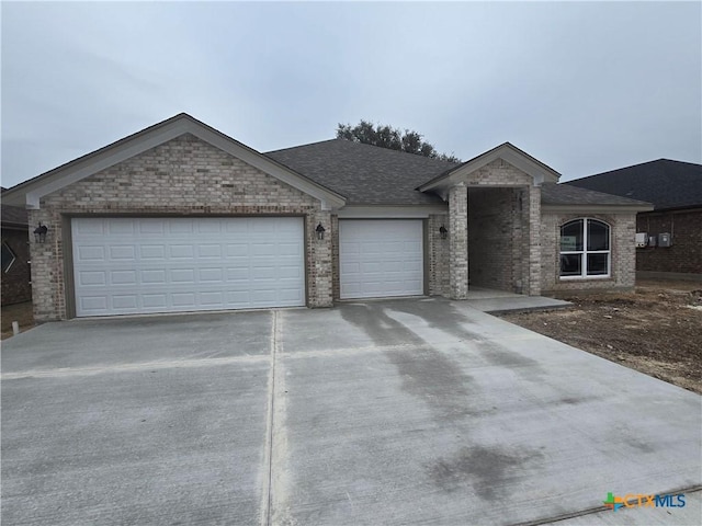 ranch-style house featuring a shingled roof, concrete driveway, brick siding, and an attached garage