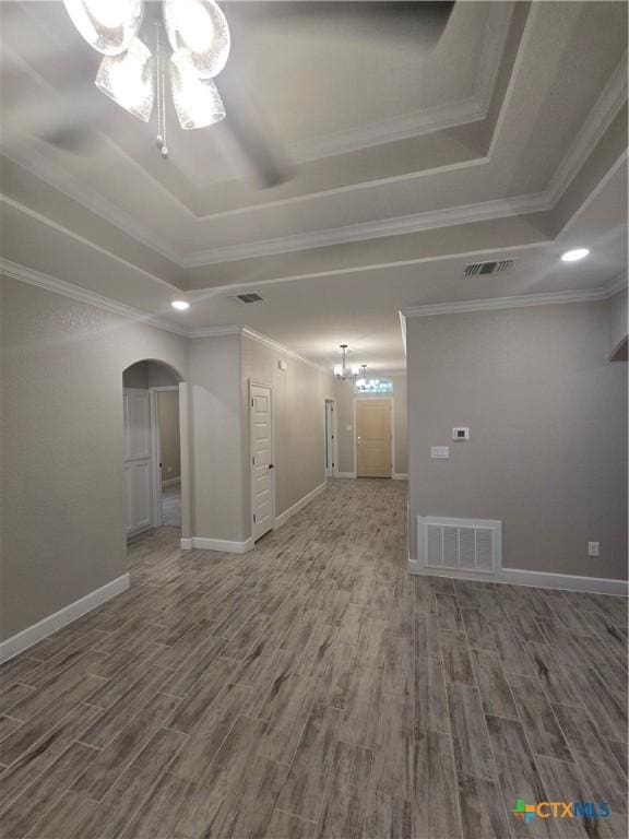 unfurnished room with a chandelier, a tray ceiling, visible vents, and wood finished floors