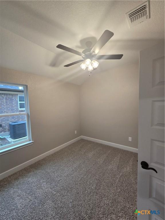 spare room with baseboards, visible vents, vaulted ceiling, a textured ceiling, and carpet flooring