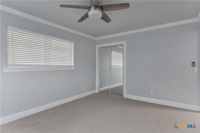 unfurnished bedroom featuring ceiling fan, carpet floors, ornamental molding, and a closet