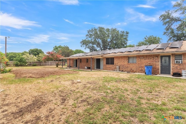 back of property featuring a yard and solar panels