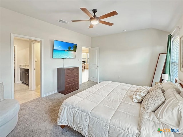 bedroom featuring lofted ceiling, light carpet, connected bathroom, and ceiling fan