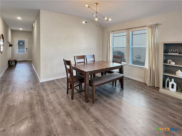 dining space with hardwood / wood-style flooring, vaulted ceiling, and an inviting chandelier