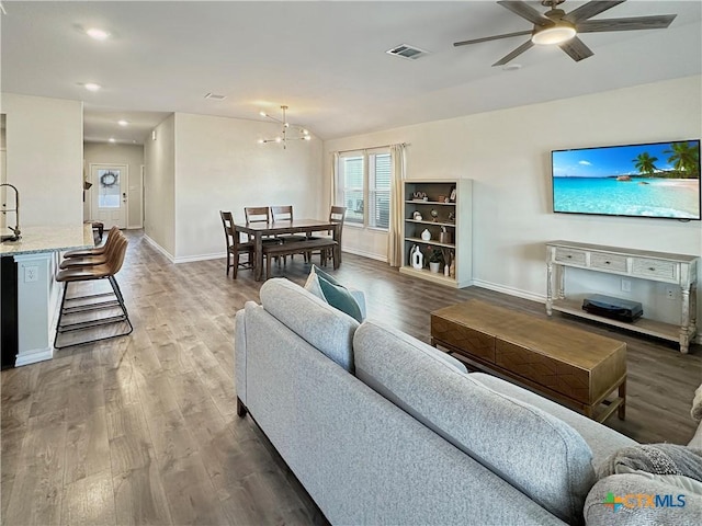 living room with sink, dark hardwood / wood-style flooring, and ceiling fan with notable chandelier