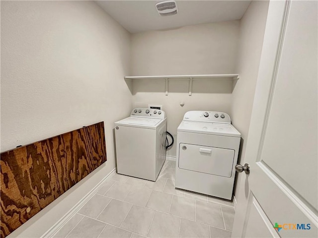 clothes washing area with washer and clothes dryer and light tile patterned floors