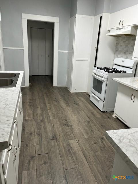 kitchen with white cabinets, white gas range, dark wood-type flooring, and sink