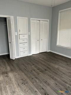 unfurnished bedroom with multiple closets and dark wood-type flooring