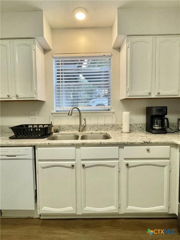 kitchen with white dishwasher, dark hardwood / wood-style flooring, sink, and white cabinets