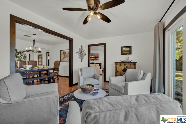 tiled living room with ceiling fan with notable chandelier