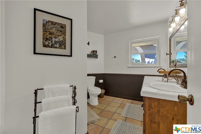 bathroom with toilet, vanity, and tile patterned flooring