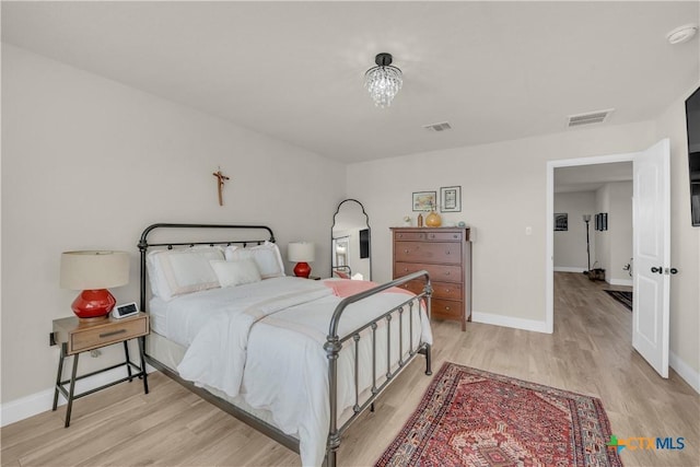 bedroom featuring visible vents, baseboards, and light wood finished floors