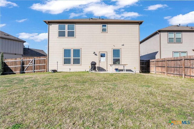 rear view of property featuring a lawn and a fenced backyard