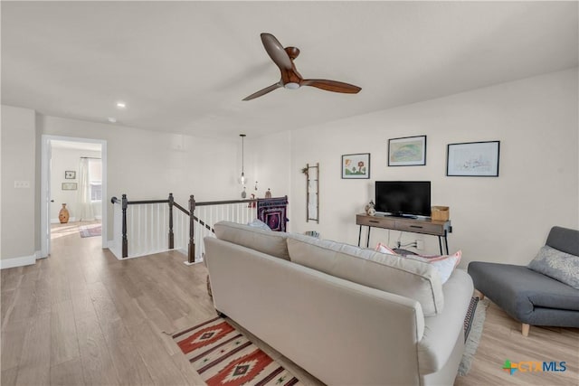 living room with light wood finished floors, baseboards, and a ceiling fan