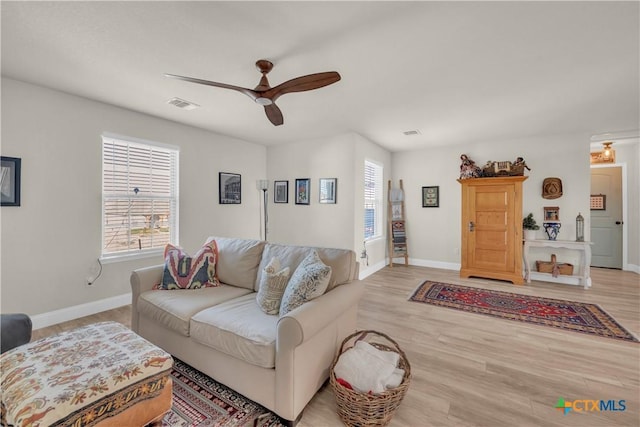 living room featuring baseboards, wood finished floors, visible vents, and ceiling fan