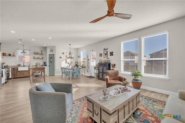 living room featuring visible vents, baseboards, recessed lighting, ceiling fan with notable chandelier, and light wood-type flooring