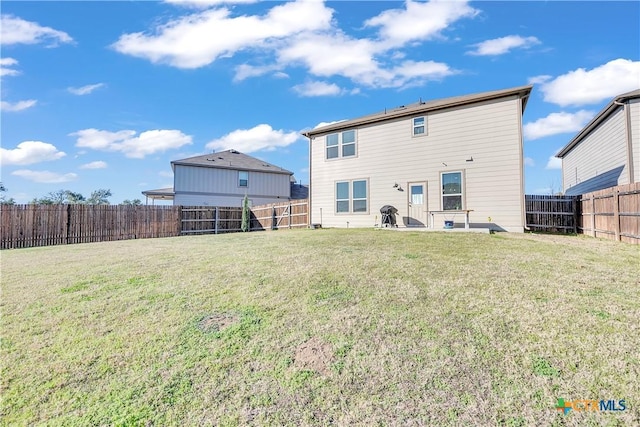 rear view of house with a lawn and a fenced backyard