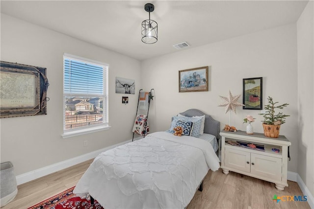 bedroom with baseboards, visible vents, and light wood finished floors