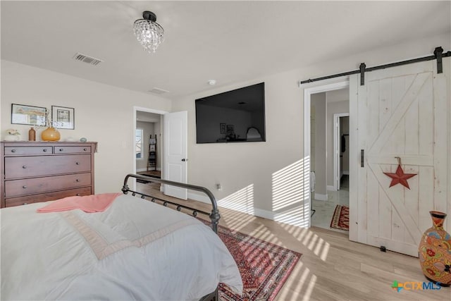 bedroom with visible vents, a barn door, and wood finished floors