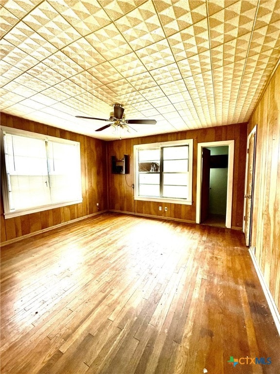 interior space featuring ceiling fan, wood walls, and hardwood / wood-style floors