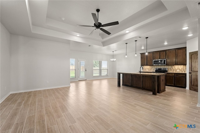 kitchen featuring light hardwood / wood-style flooring, dark brown cabinetry, an island with sink, and a raised ceiling