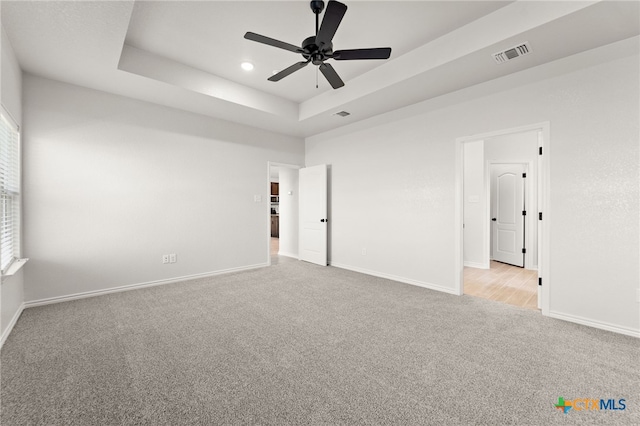 unfurnished room featuring light carpet, a raised ceiling, and ceiling fan