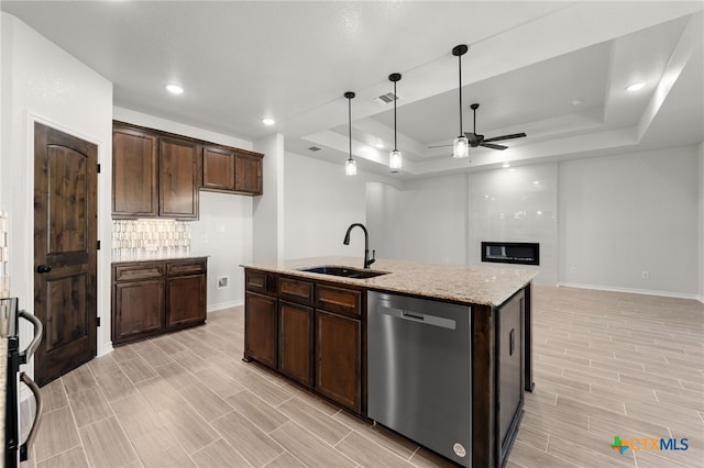 kitchen with stainless steel appliances, light stone countertops, sink, and a tray ceiling