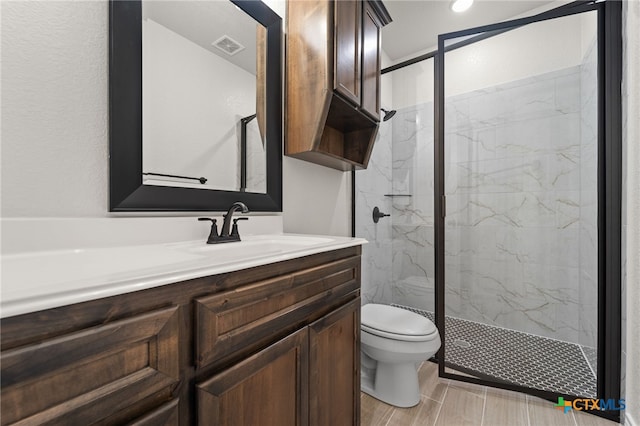 bathroom featuring a shower with door, vanity, and toilet