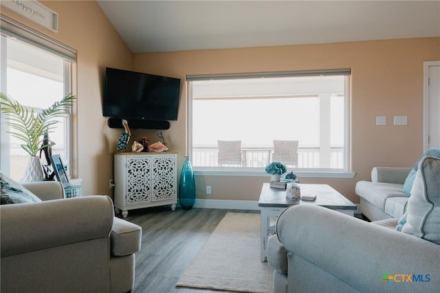 living room with a healthy amount of sunlight, hardwood / wood-style flooring, and vaulted ceiling