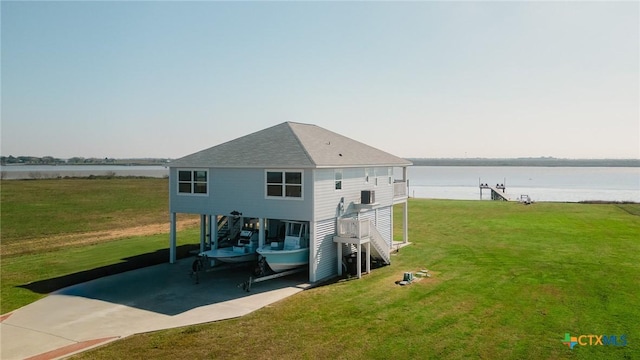 back of property with a yard, a water view, and a carport