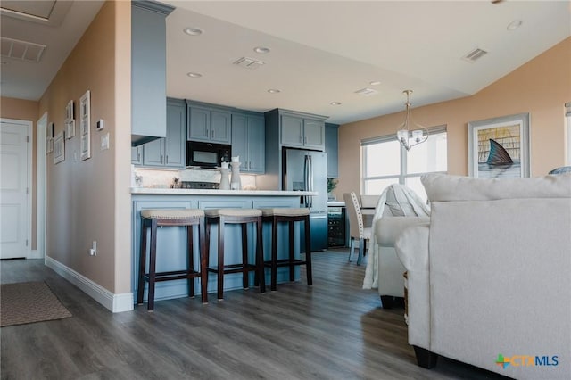 kitchen featuring kitchen peninsula, dark hardwood / wood-style flooring, decorative light fixtures, stainless steel refrigerator with ice dispenser, and a kitchen breakfast bar