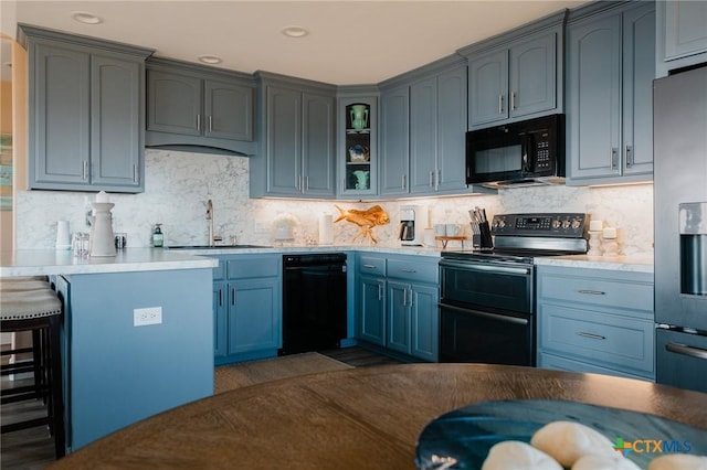 kitchen with black appliances, wine cooler, sink, a breakfast bar area, and decorative backsplash