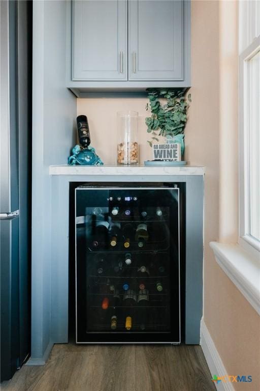 bar with stainless steel refrigerator, wine cooler, and wood-type flooring