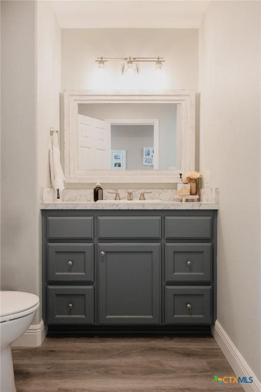 bathroom with toilet, vanity, and wood-type flooring