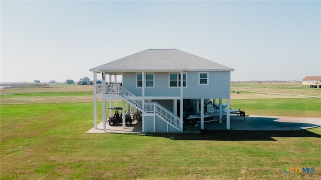 back of property with a patio area, a yard, and a rural view