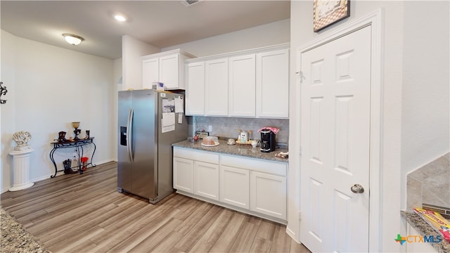 kitchen with white cabinets, light stone countertops, stainless steel refrigerator with ice dispenser, and light hardwood / wood-style flooring