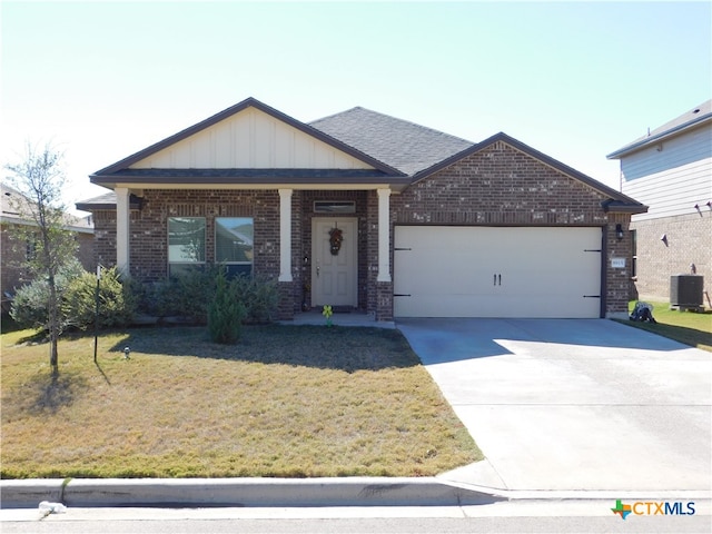 view of front of house featuring cooling unit, a front yard, and a garage