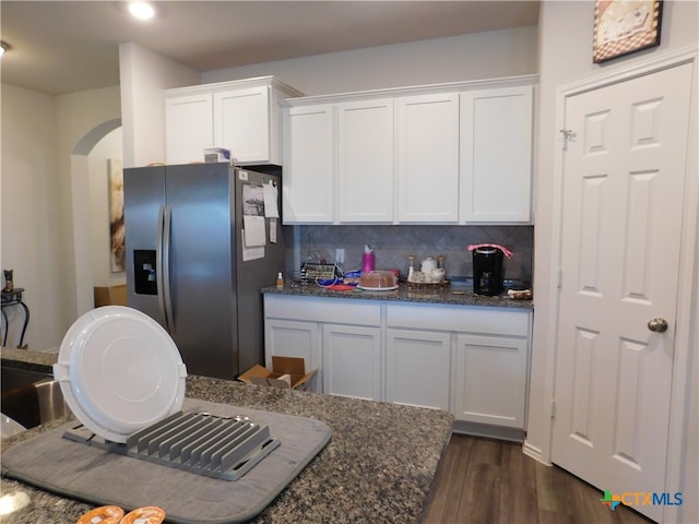 kitchen featuring white cabinets, dark stone countertops, dark hardwood / wood-style flooring, and stainless steel refrigerator with ice dispenser