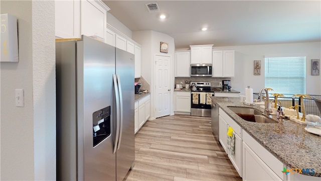 kitchen featuring white cabinets, appliances with stainless steel finishes, light hardwood / wood-style floors, and sink